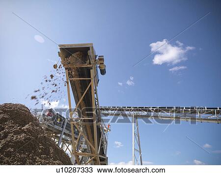 Stock Image - Stones pouring in pile from conveyor. Fotosearch