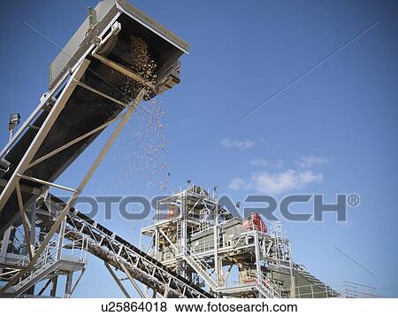 Stock Photo - Stones pouring in pile from conveyor. Fotosearch