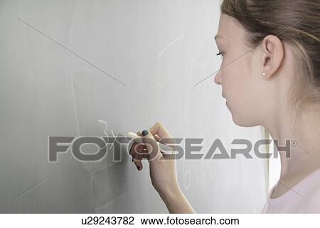 Stock Image - Student writing math on chalkboard. Fotosearch