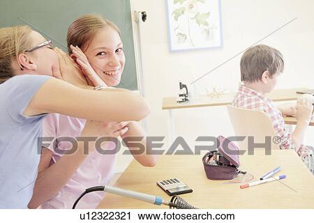 Stock Image - Students whispering in technology lab. Fotosearch