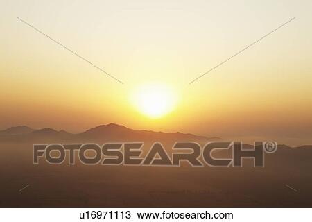 Sun setting over foggy landscape View Large Photo Image Stock Image - Sun setting over foggy landscape. Fotosearch