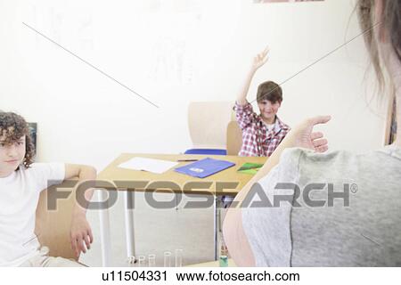 Stock Image - Teacher calling on student in class. Fotosearch