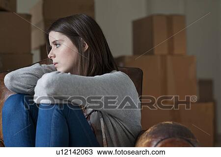 Stock Image - Teenage girl in armchair in new home. Fotosearch
