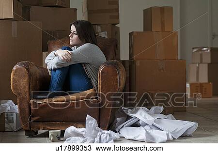 Stock Image - Teenage girl in armchair in new home. Fotosearch