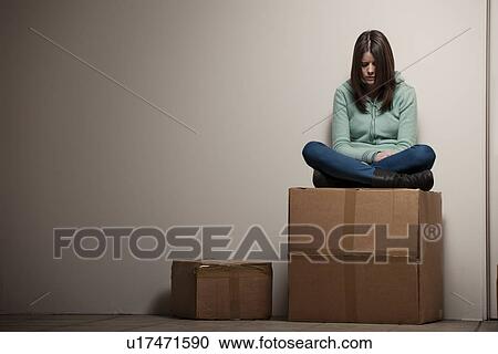 Stock Image - Teenage girl sitting on cardboard box. Fotosearch