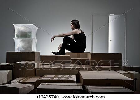 Stock Image - Teenage girl sitting on cardboard boxes. Fotosearch