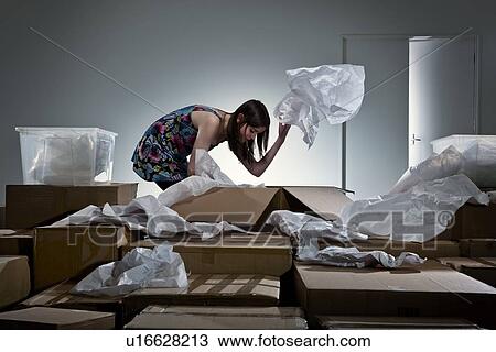 Stock Image - Teenage girl unpacking cardboard boxes. Fotosearch