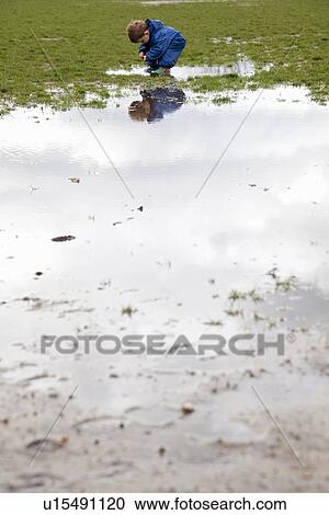 Stock Image - Toddler boy walking in puddle. Fotosearch