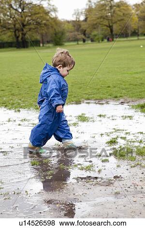 Toddler boy walking in puddle View Large Photo Image Stock Photo - Toddler boy walking in puddle. Fotosearch