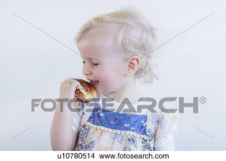 Toddler girl eating pastry indoors View Large Photo Image Picture - Toddler girl eating pastry indoors. Fotosearch