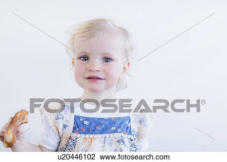Toddler girl eating pastry indoors View Large Photo Image Stock Image - Toddler girl eating pastry indoors. Fotosearch