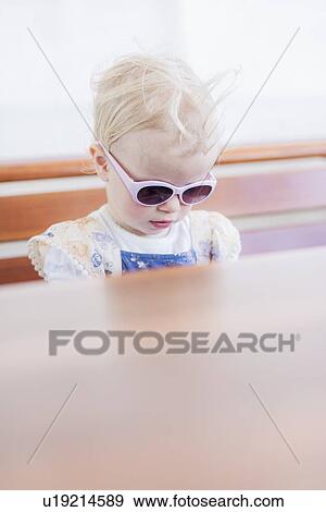 Stock Photo - Toddler girl wearing sunglasses indoors. Fotosearch