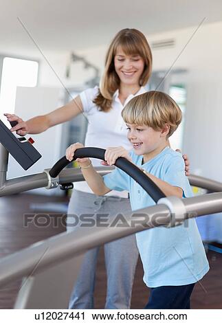 Stock Image - Trainer working with boy in gym. Fotosearch