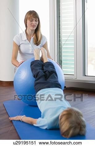 Stock Image - Trainer working with boy in gym. Fotosearch