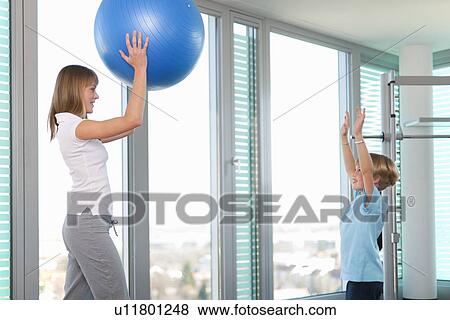 Stock Photo - Trainer working with boy in gym. Fotosearch