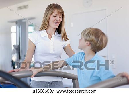 Stock Photo - Trainer working with boy in gym. Fotosearch