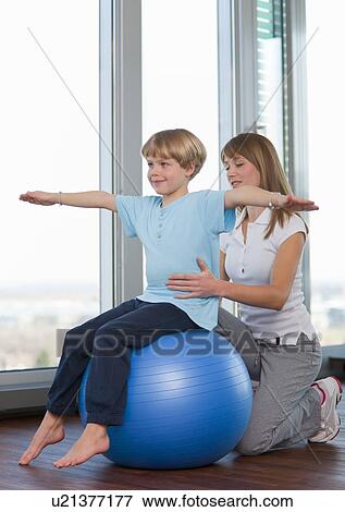 Stock Photo - Trainer working with boy in gym. Fotosearch
