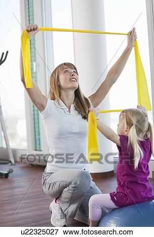 Stock Photo - Trainer working with girl in gym. Fotosearch