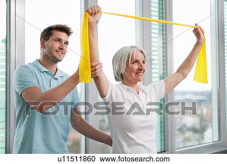 Stock Image - Trainer working with woman in gym. Fotosearch