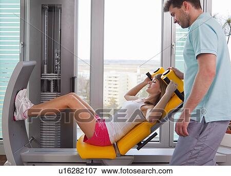 Stock Photo - Trainer working with woman in gym. Fotosearch