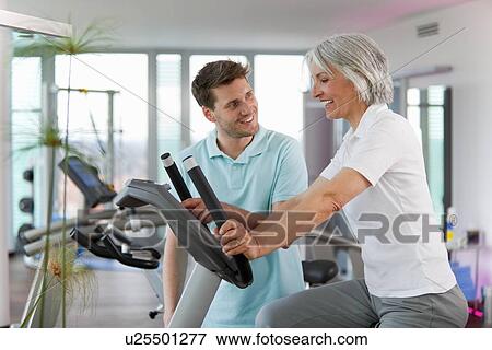Stock Photo - Trainer working with woman in gym. Fotosearch