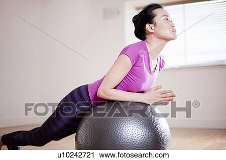 Woman balancing on ball in yoga studio View Large Photo Image Stock Image - Woman balancing on ball in yoga studio. Fotosearch