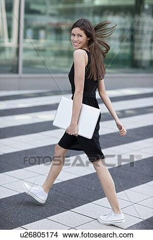 Picture - Woman carrying laptop on city street. Fotosearch