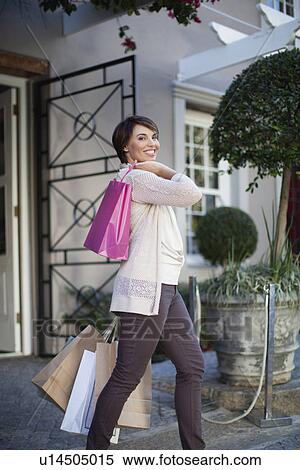 Stock Photography - Woman carrying shopping bags outdoors. Fotosearch