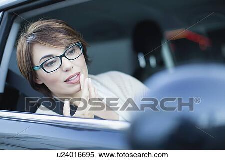 Woman checking makeup in side mirror View Large Photo Image Stock Photography - Woman checking makeup in side mirror. Fotosearch