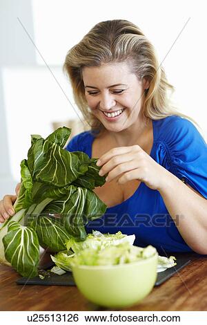 Stock Photograph - Woman chopping vegetables in kitchen. Fotosearch