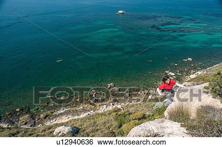 Woman climbing rocky coastal cliff View Large Photo Image Stock Photograph - Woman climbing rocky coastal cliff. Fotosearch