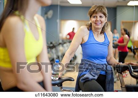 Stock Image - Woman climbing spin machine in gym. Fotosearch