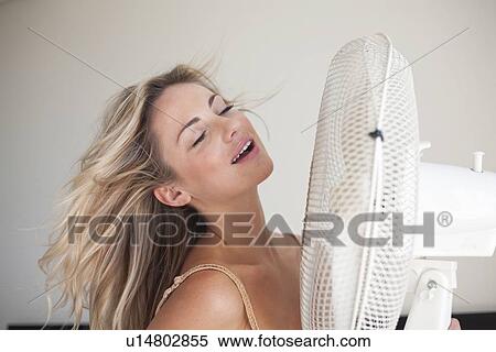 Stock Photography - Woman cooling herself with fan. Fotosearch