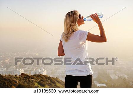 Woman drinking water on hilltop View Large Photo Image Stock Image - Woman drinking water on hilltop. Fotosearch