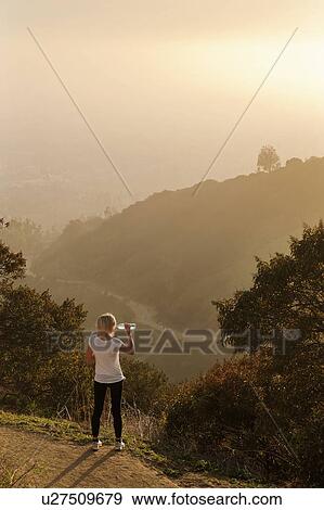 Woman drinking water on hilltop View Large Photo Image Stock Photo - Woman drinking water on hilltop. Fotosearch