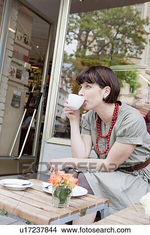 Picture - Woman having coffee at sidewalk cafe. Fotosearch