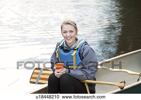 Stock Image - Woman having coffee in canoe. Fotosearch