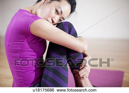 Woman hugging her knee on yoga mat View Large Photo Image Stock Photograph - Woman hugging her knee on yoga mat. Fotosearch