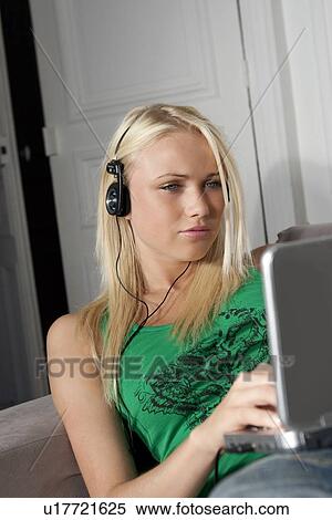 Stock Photography - Woman in headphones using laptop. Fotosearch