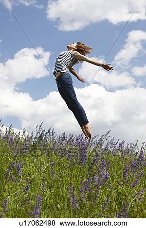 Stock Photo - Woman jumping over tall grass. Fotosearch