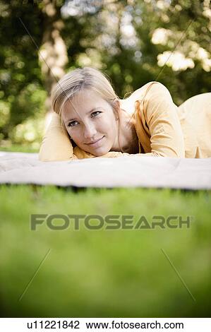 Woman laying on blanket in park View Large Photo Image Stock Image - Woman laying on blanket in park. Fotosearch
