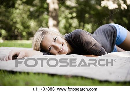 Woman laying on blanket in park View Large Photo Image Stock Image - Woman laying on blanket in park. Fotosearch