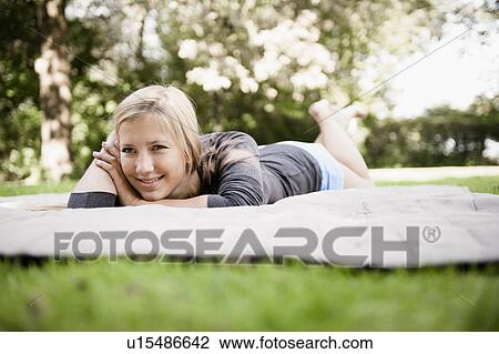 Woman laying on blanket in park View Large Photo Image Stock Image - Woman laying on blanket in park. Fotosearch