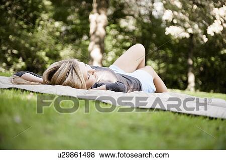 Stock Photo - Woman laying on blanket in park. Fotosearch