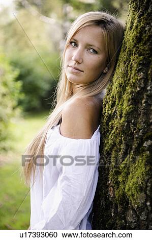 Woman leaning against tree outdoors View Large Photo Image Stock Image - Woman leaning against tree outdoors. Fotosearch