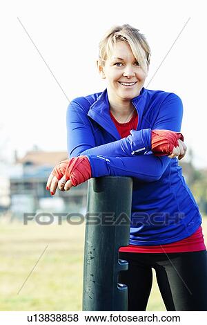 Stock Photo - Woman leaning on pole outdoors. Fotosearch