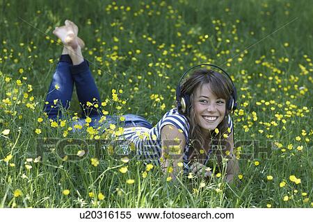 Woman listening to headphones in grass View Large Photo Image Stock Photography - Woman listening to headphones in grass. Fotosearch