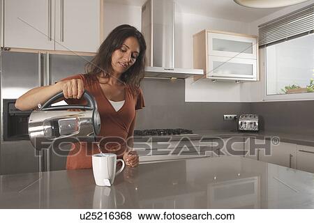 Woman making cup of tea in kitchen View Large Photo Image Stock Photo - Woman making cup of tea in kitchen. Fotosearch
