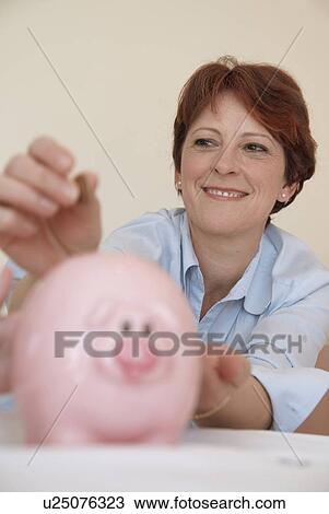 Woman putting money in piggy bank View Large Photo Image Stock Image - Woman putting money in piggy bank. Fotosearch