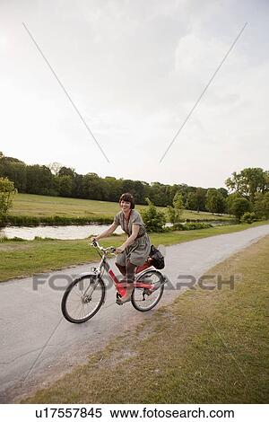 Woman riding bicycle on rural road View Large Photo Image Stock Photography - Woman riding bicycle on rural road. Fotosearch